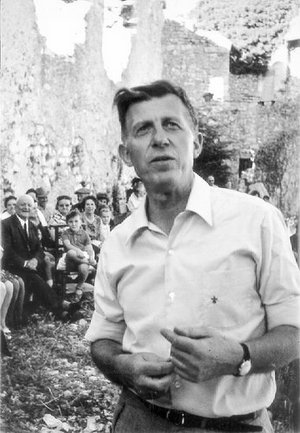 Harald Falk Mann im weißen Oberhemd mit Chor im Hintergrund