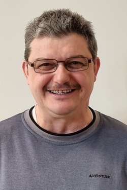Mann mit Brille braunen, graumelierten Haaren und einem grauen Pullover