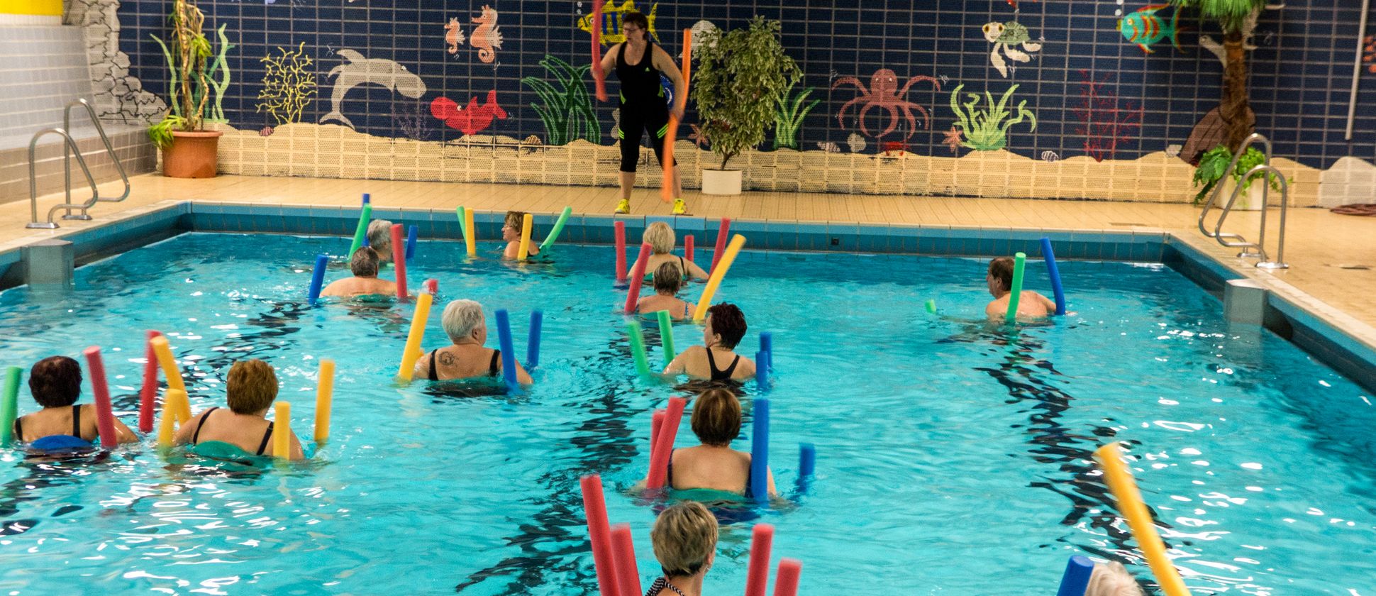 Menschen im Schwimmbad mit Poolnudeln