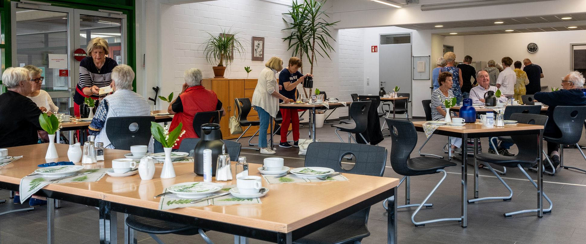 Ganz viele Menschen frühstück gemeinsam in einem großen Saal