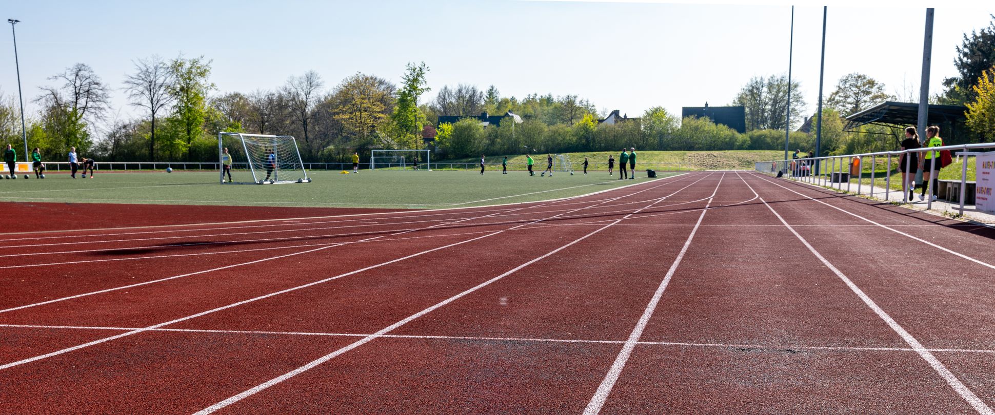 Tartanlaufbahn und Kunstrasenplatz mit Fußballspielenden Kindern