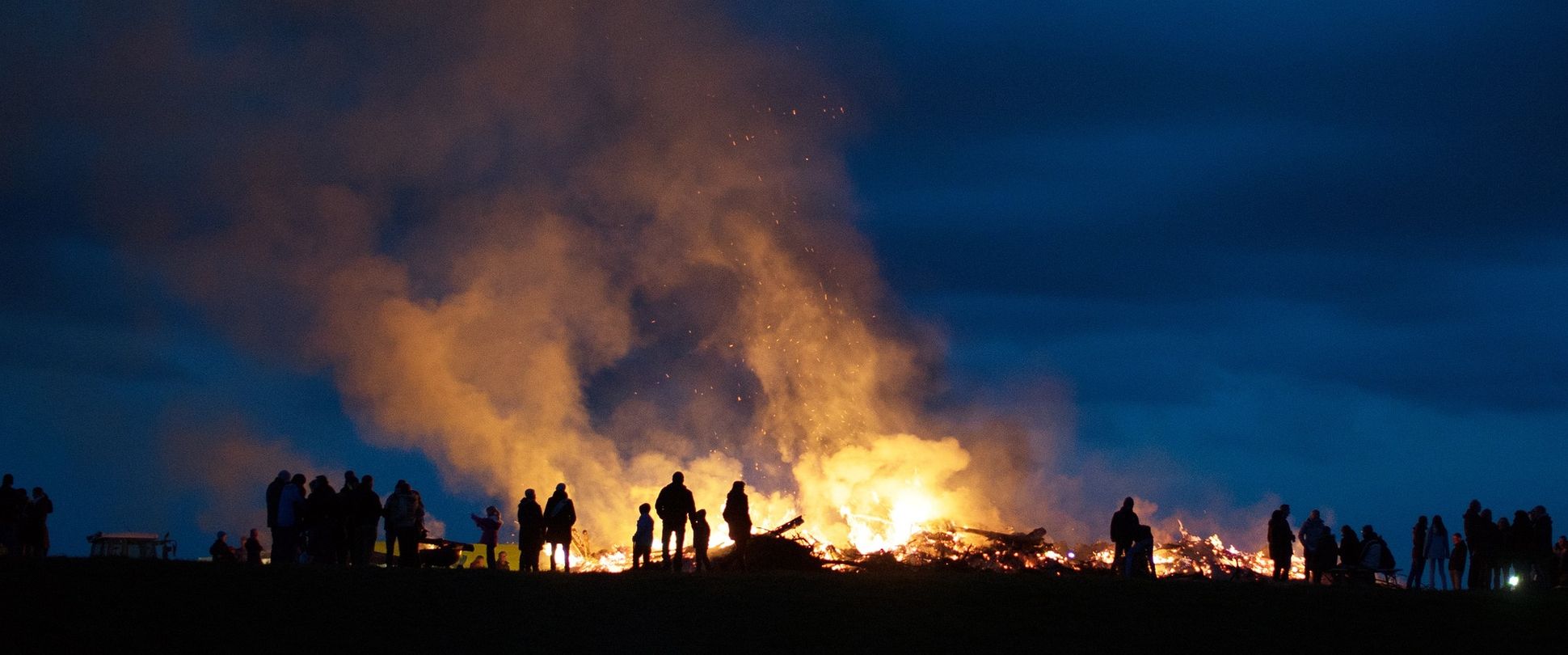 Osterfeuer - Menschen stehen an einem großen Feuer