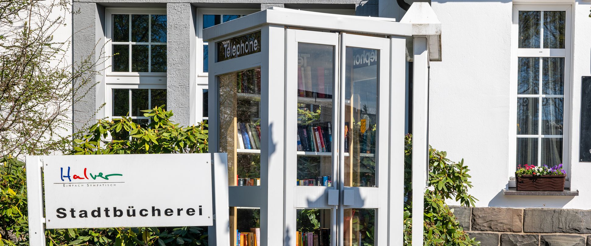 Schild mit Aufschrift und öffentlicher Bücherschrank