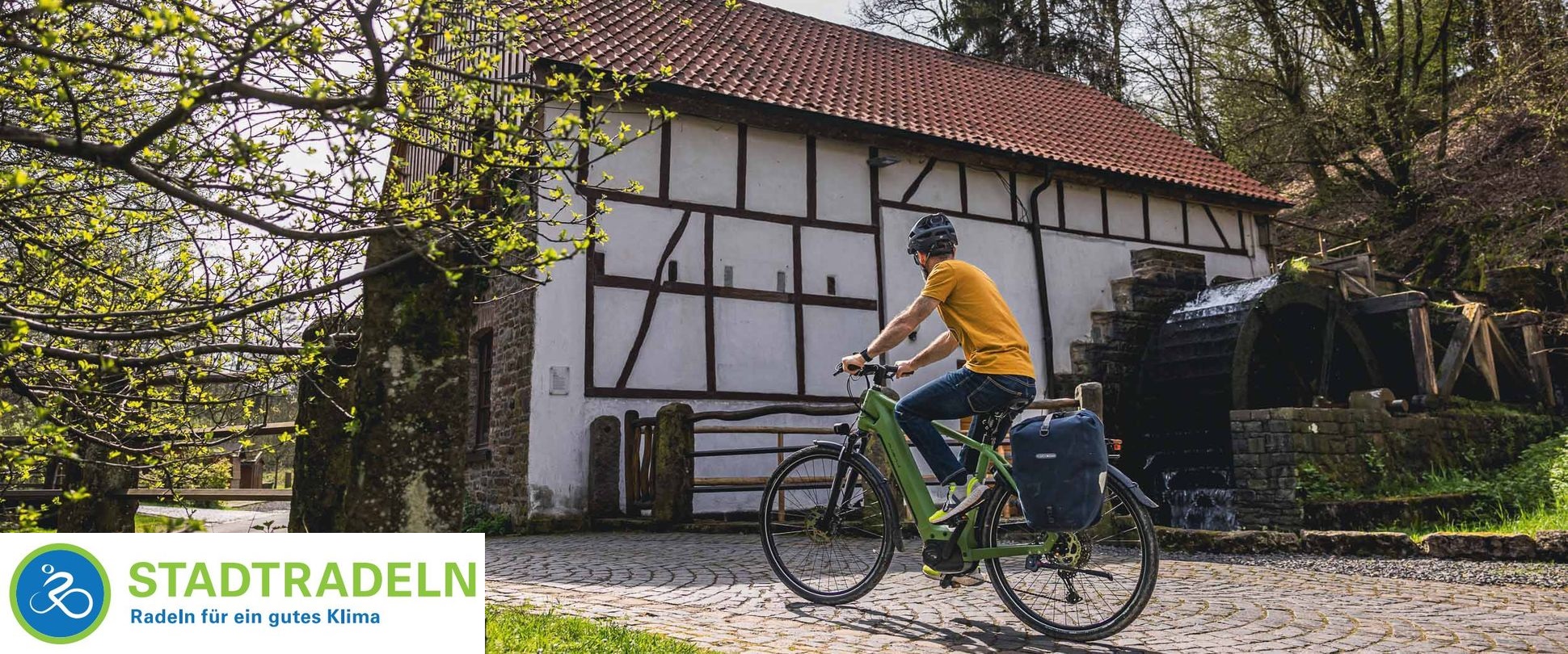 Mann auf einem Fahrrad vor einem Wasserrad