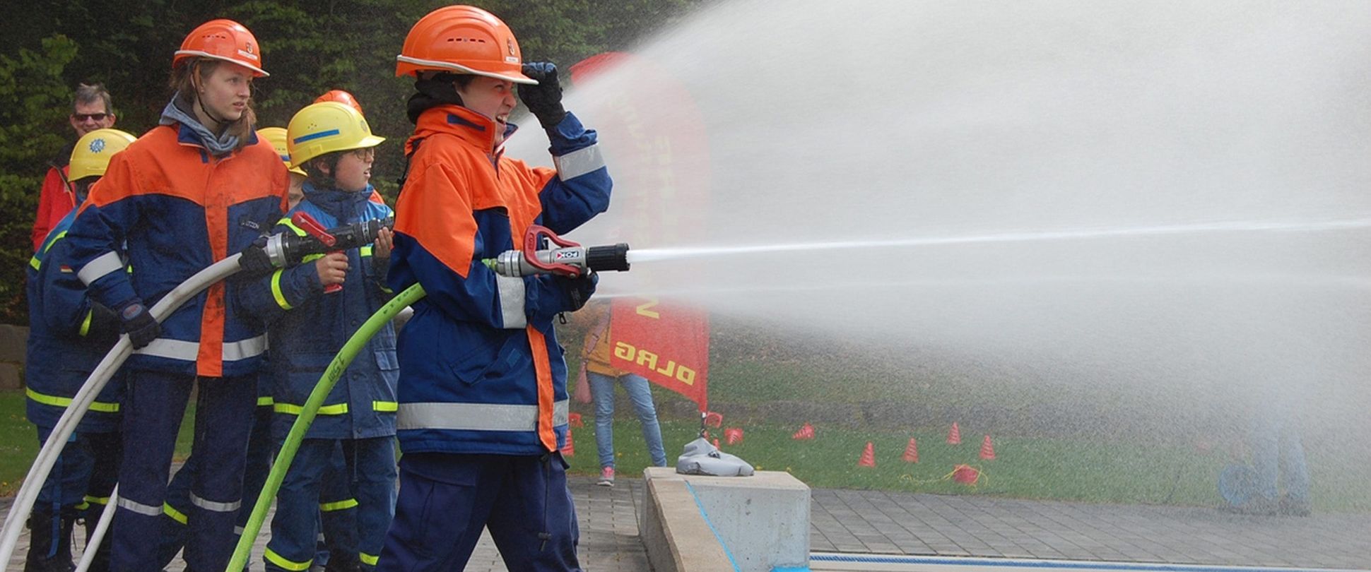 Junge Feuerwehrleute mit Schlauch