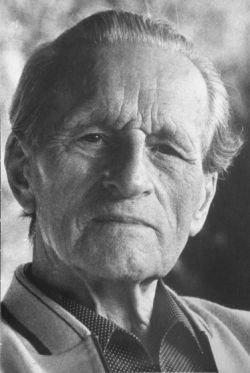 Fritz Kuhne Mann mit getupftem Hemd und Strickjacke